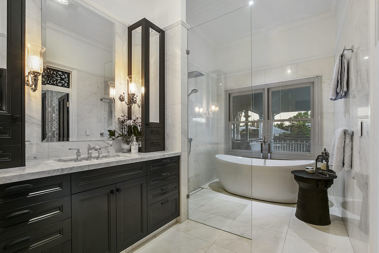 A bathroom with a tub , sinks , mirrors and a walk in shower.