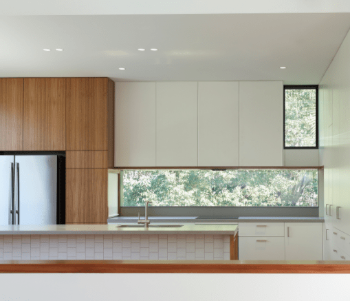 A kitchen with white cabinets and a large window