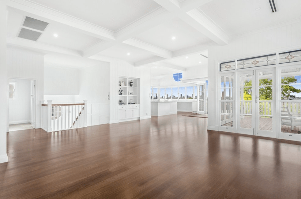 An empty living room with hardwood floors and white walls.