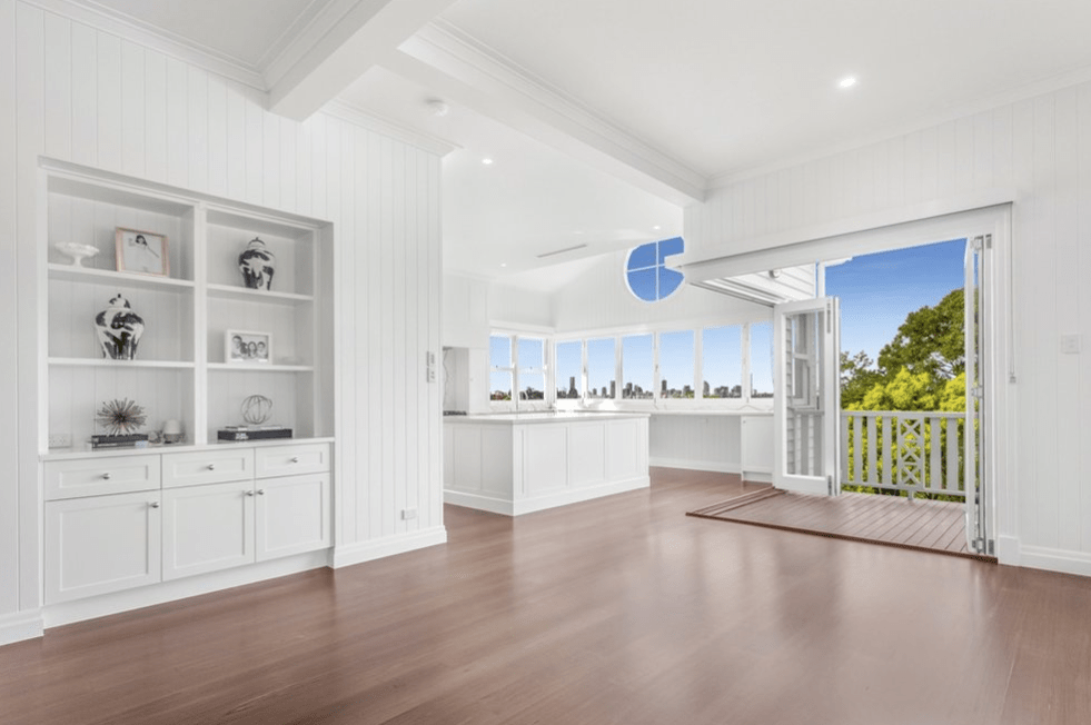 An empty living room with hardwood floors and white cabinets.
