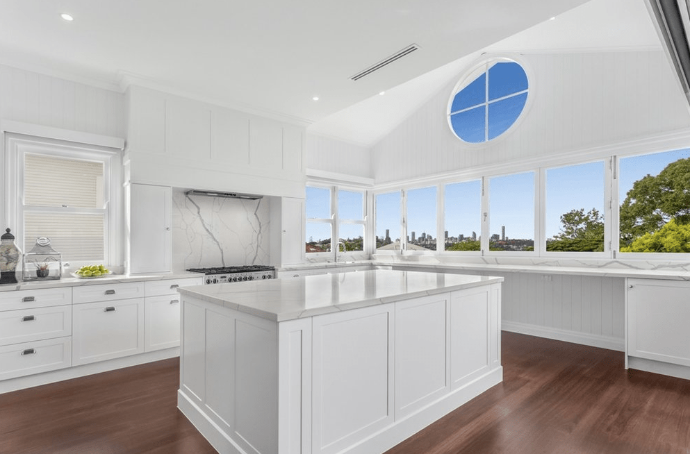 There is a large island in the middle of the kitchen with a lot of windows.