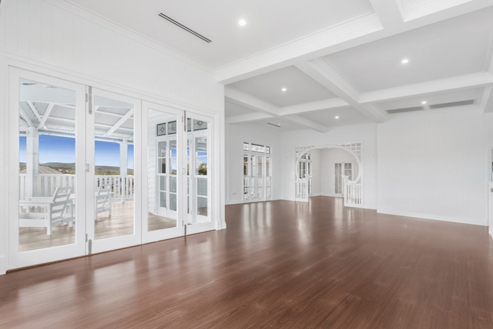A large empty room with hardwood floors and lots of windows.