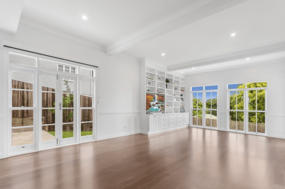 An empty living room with hardwood floors and lots of windows.