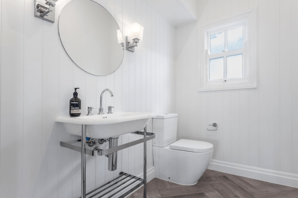 A bathroom with a sink , toilet , mirror and window.