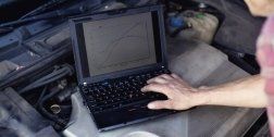 persona mettre batte i tasti di un computer posizionato sopra il cofano di un automobile