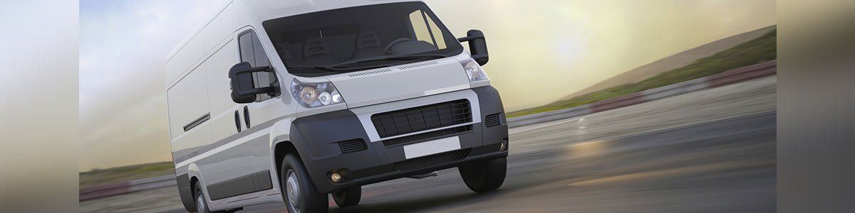 White cargo van driving on a road with a blurred background.