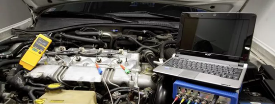 A laptop computer is sitting on top of a car engine.