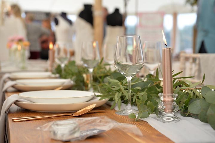 A table set for a wedding reception with plates , glasses , and candles.