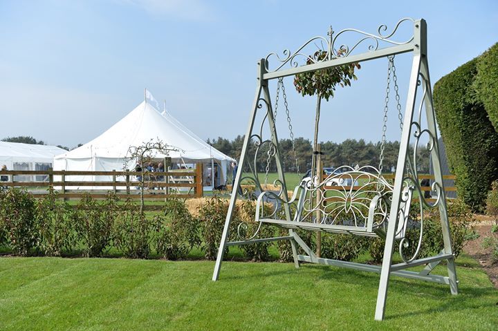 A swing is sitting in the middle of a lush green field.
