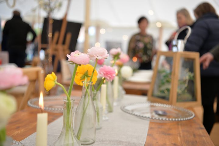A table with vases of flowers and candles on it.
