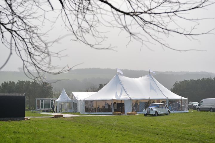 A large white tent is sitting in the middle of a grassy field.