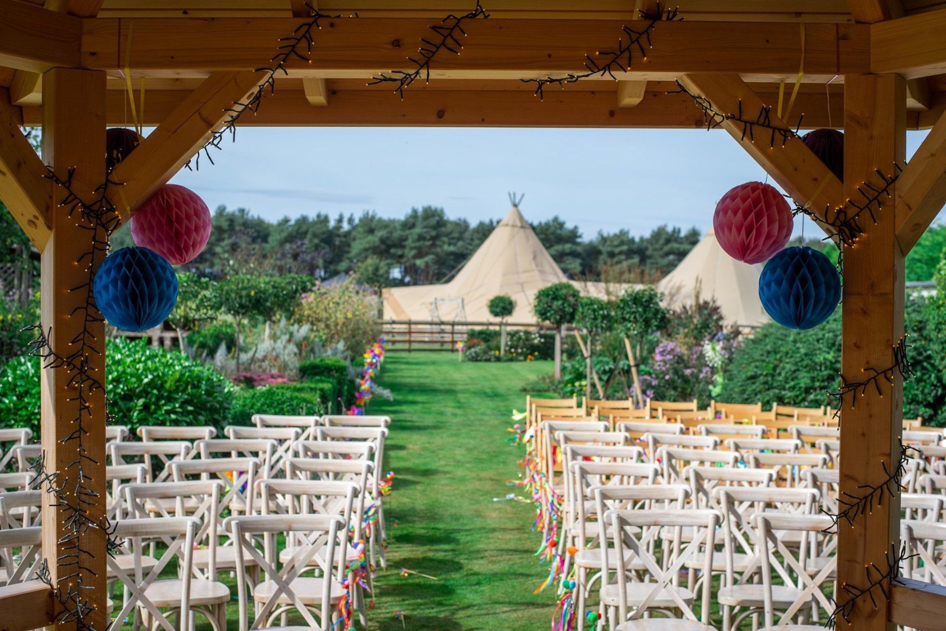 A row of chairs are lined up for a wedding ceremony under a gazebo.