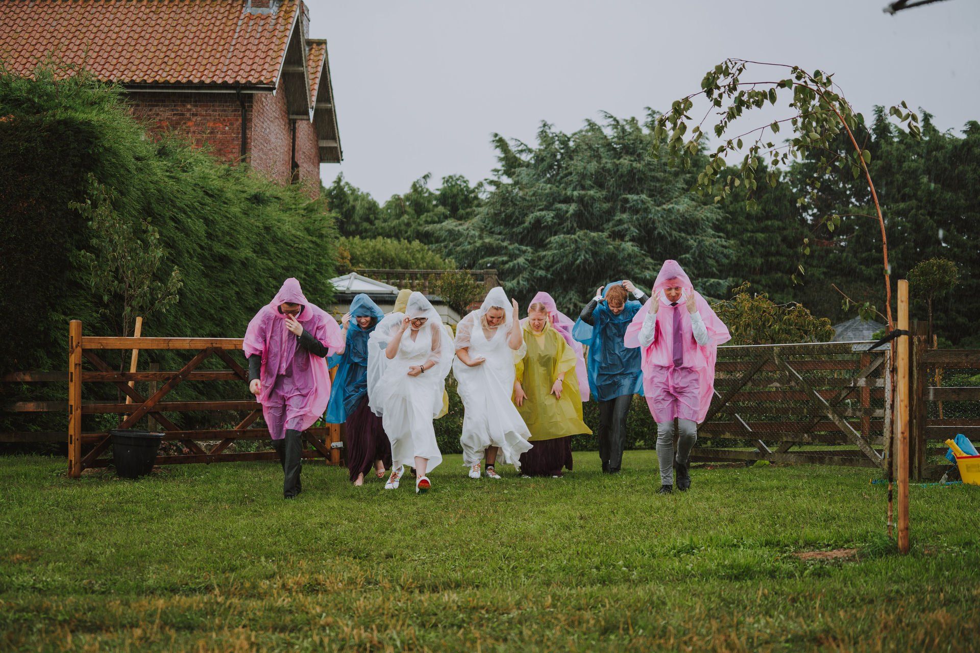 A group of people in raincoats are running in a field.