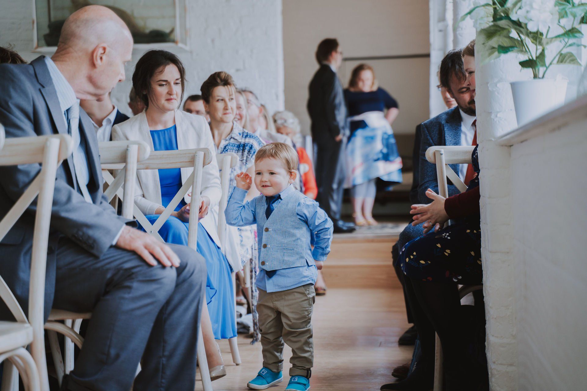 A little boy is walking down the aisle at a wedding.