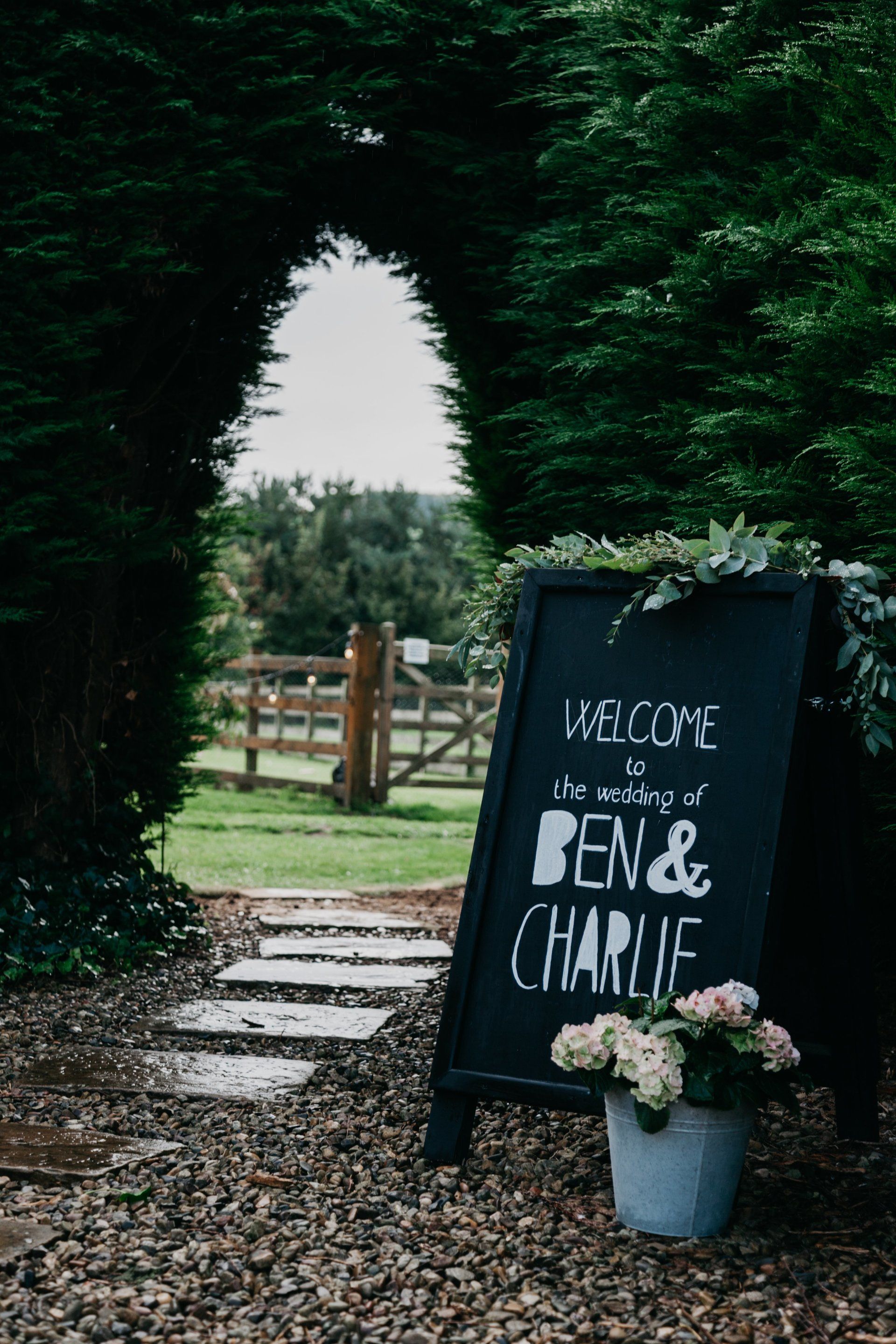 A blackboard with the words `` welcome to the wedding of ben & charlie '' written on it.