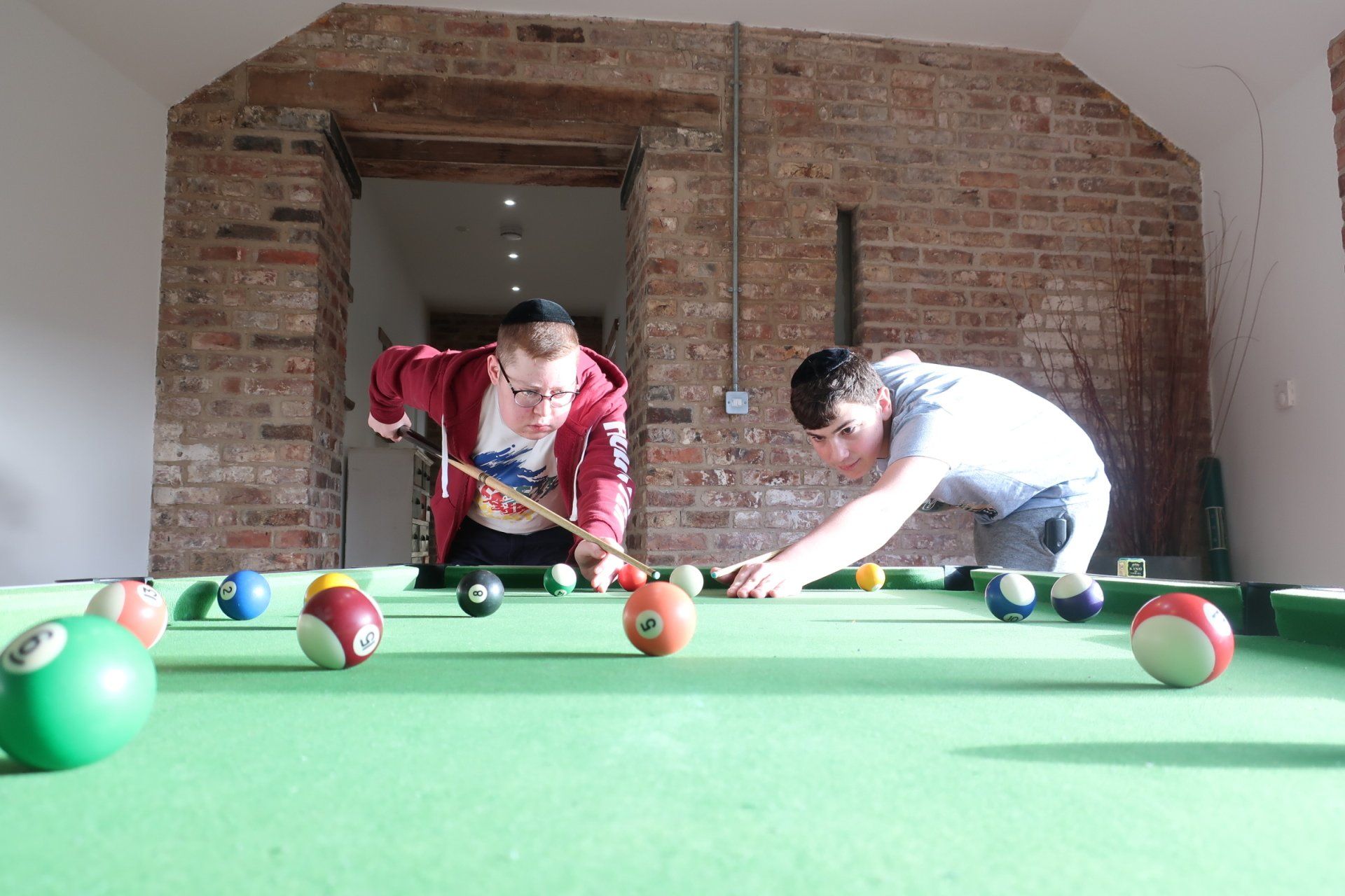 Two men are playing pool on a green pool table