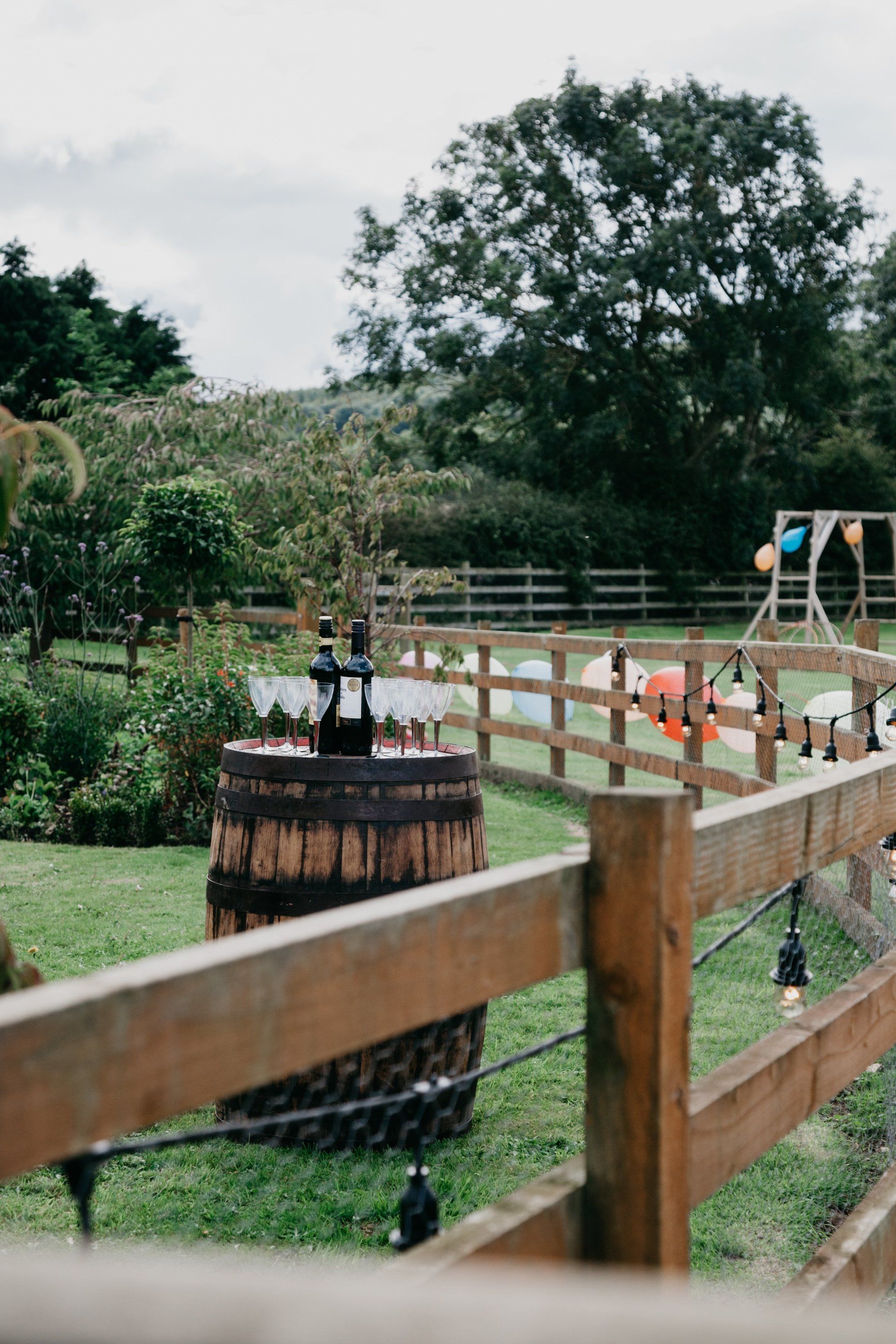 A wooden fence with a barrel in the middle of a field.