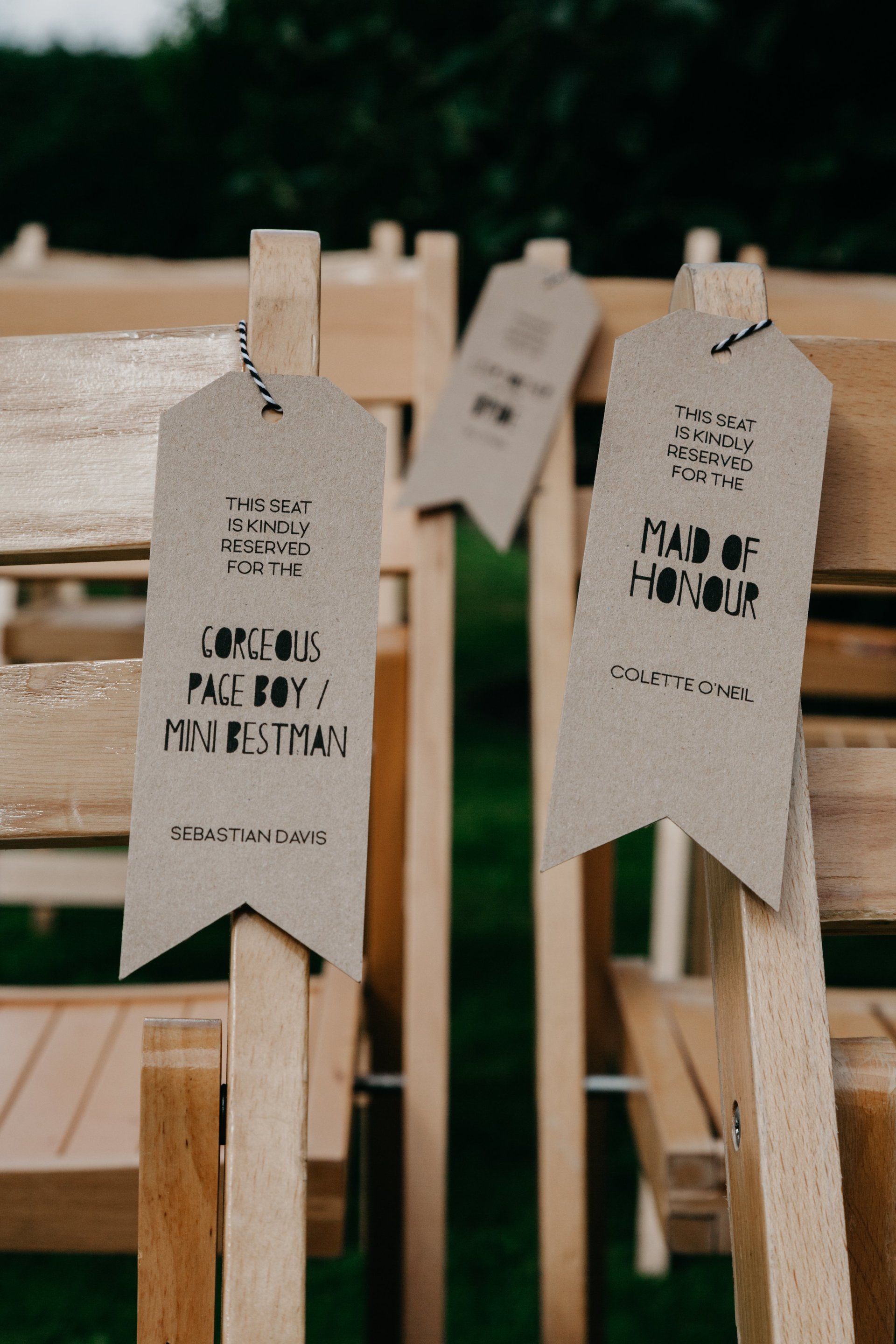 A row of wooden chairs with ribbons on them that say made of honor