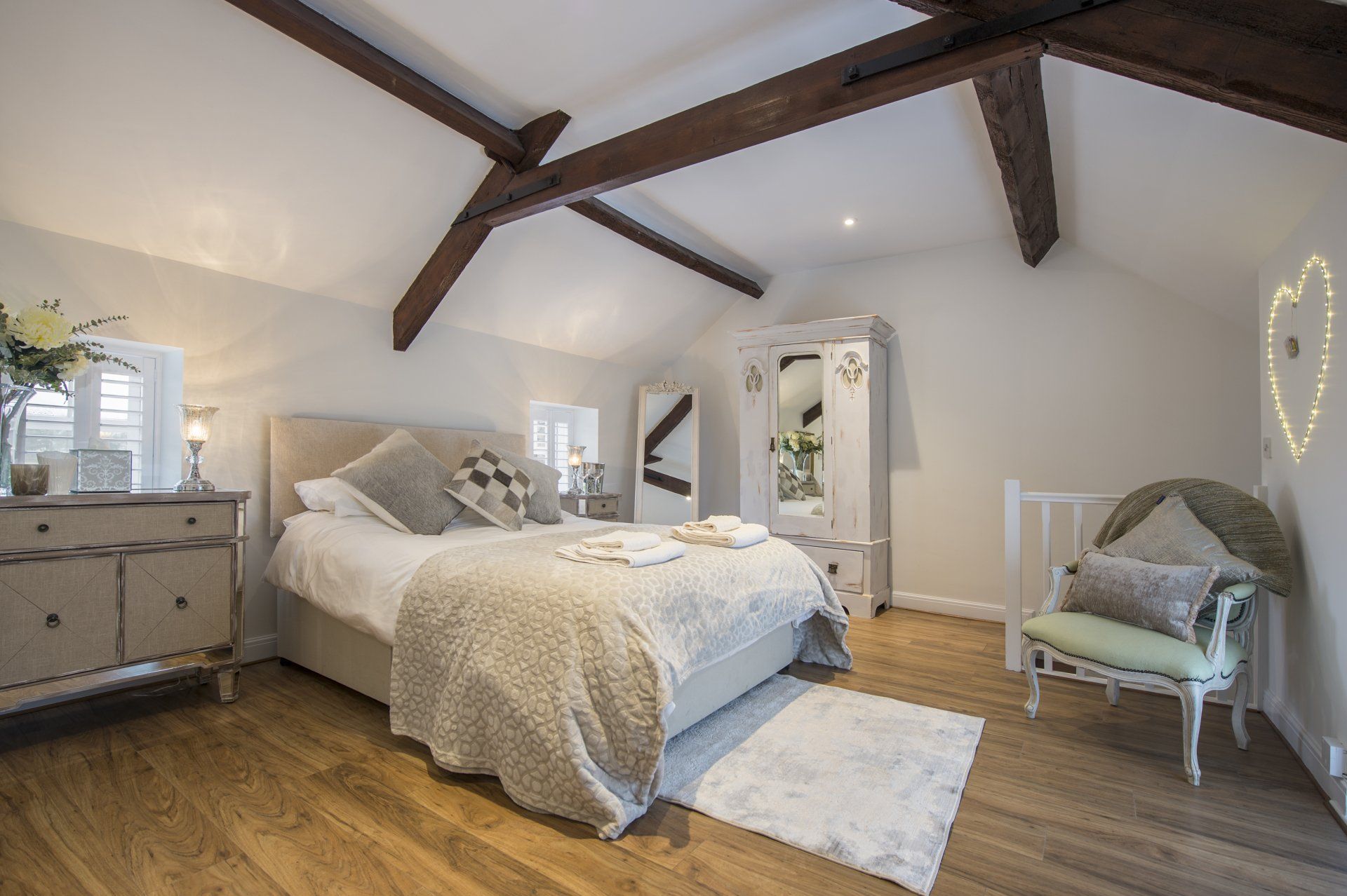 A bedroom with a bed , dresser , chair and a heart on the wall.