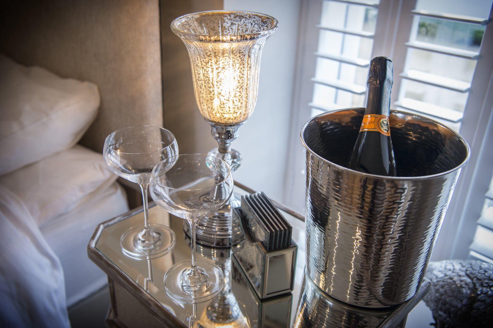 A bottle of champagne is in a silver bucket on a table.