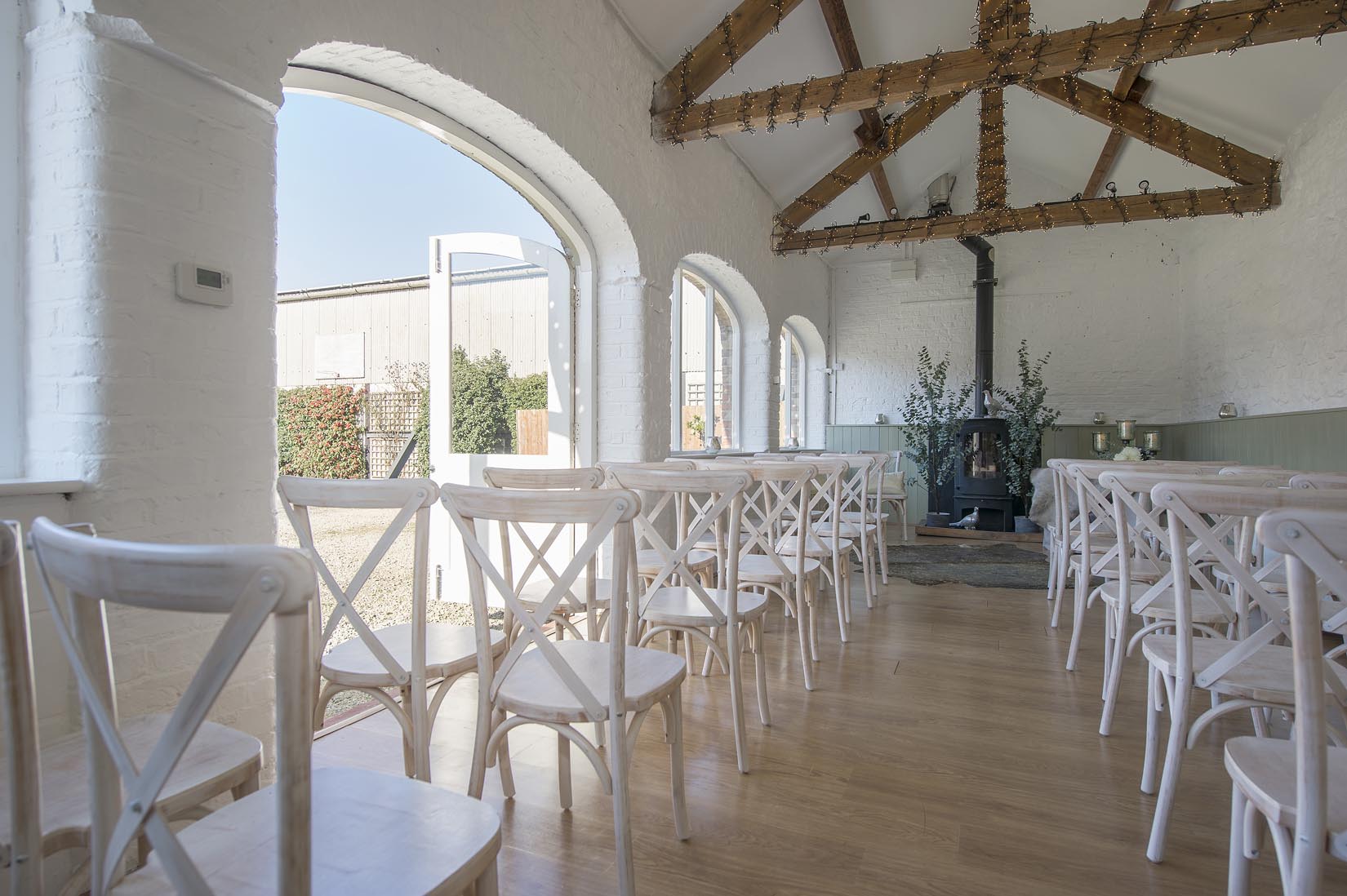 A row of white chairs are lined up in a room with arched windows.