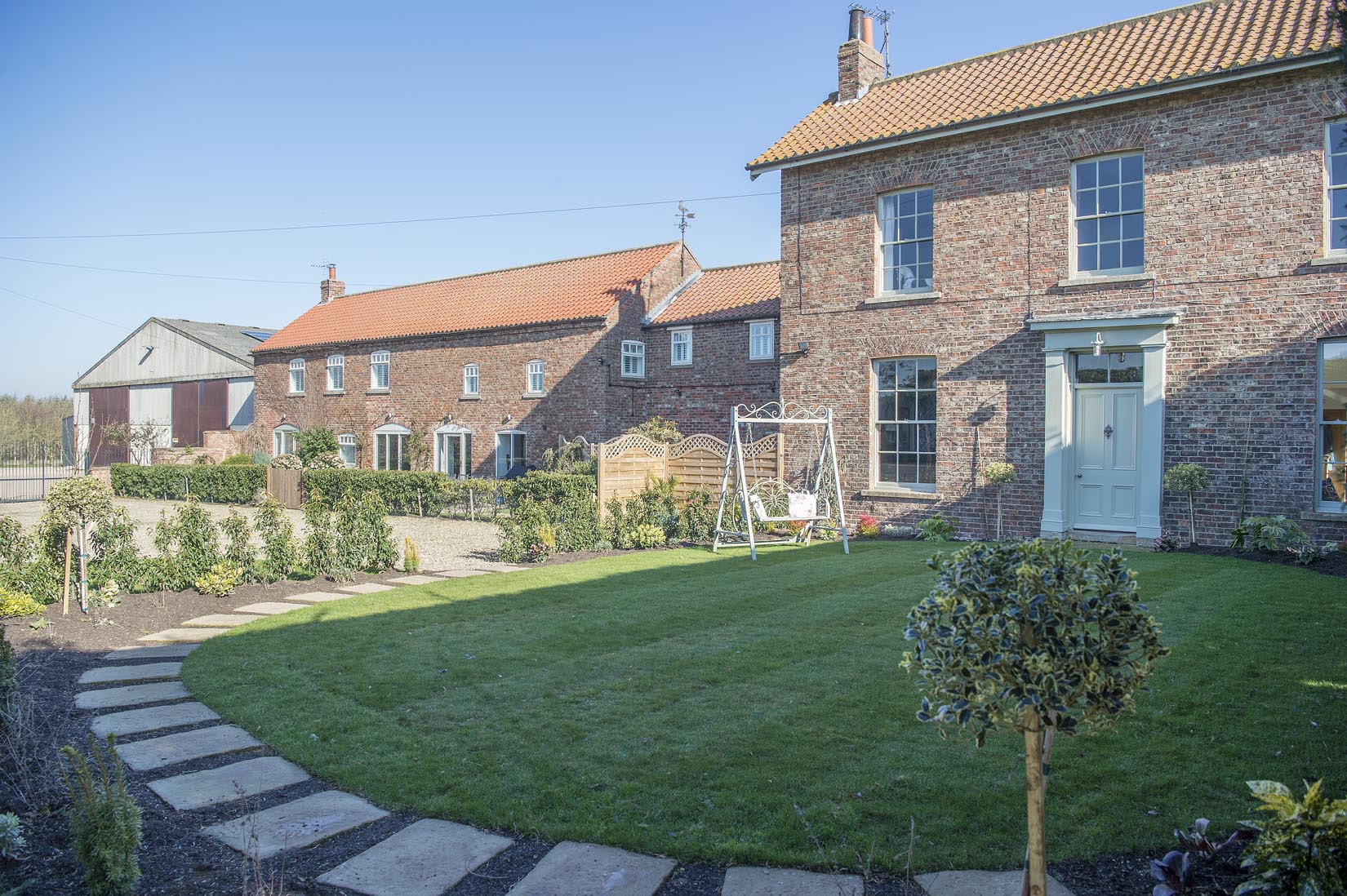 A brick house with a lush green lawn in front of it.