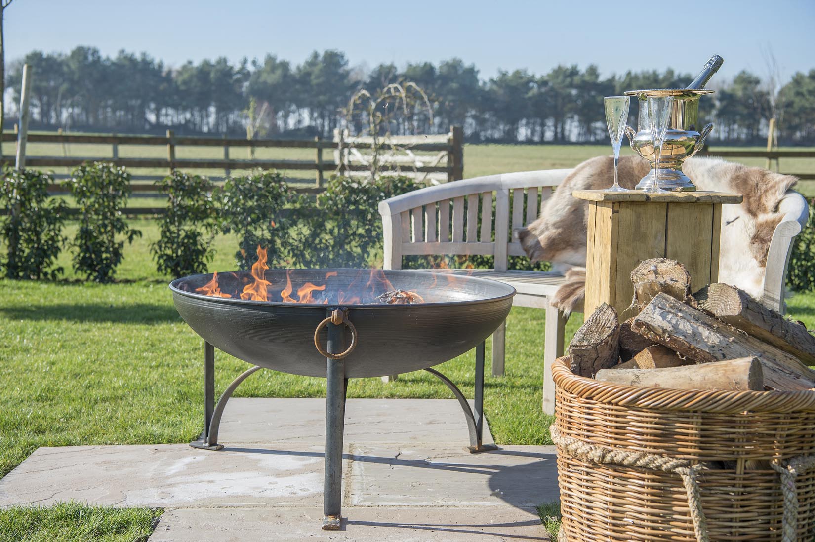 A fire pit is sitting in the middle of a lush green field.