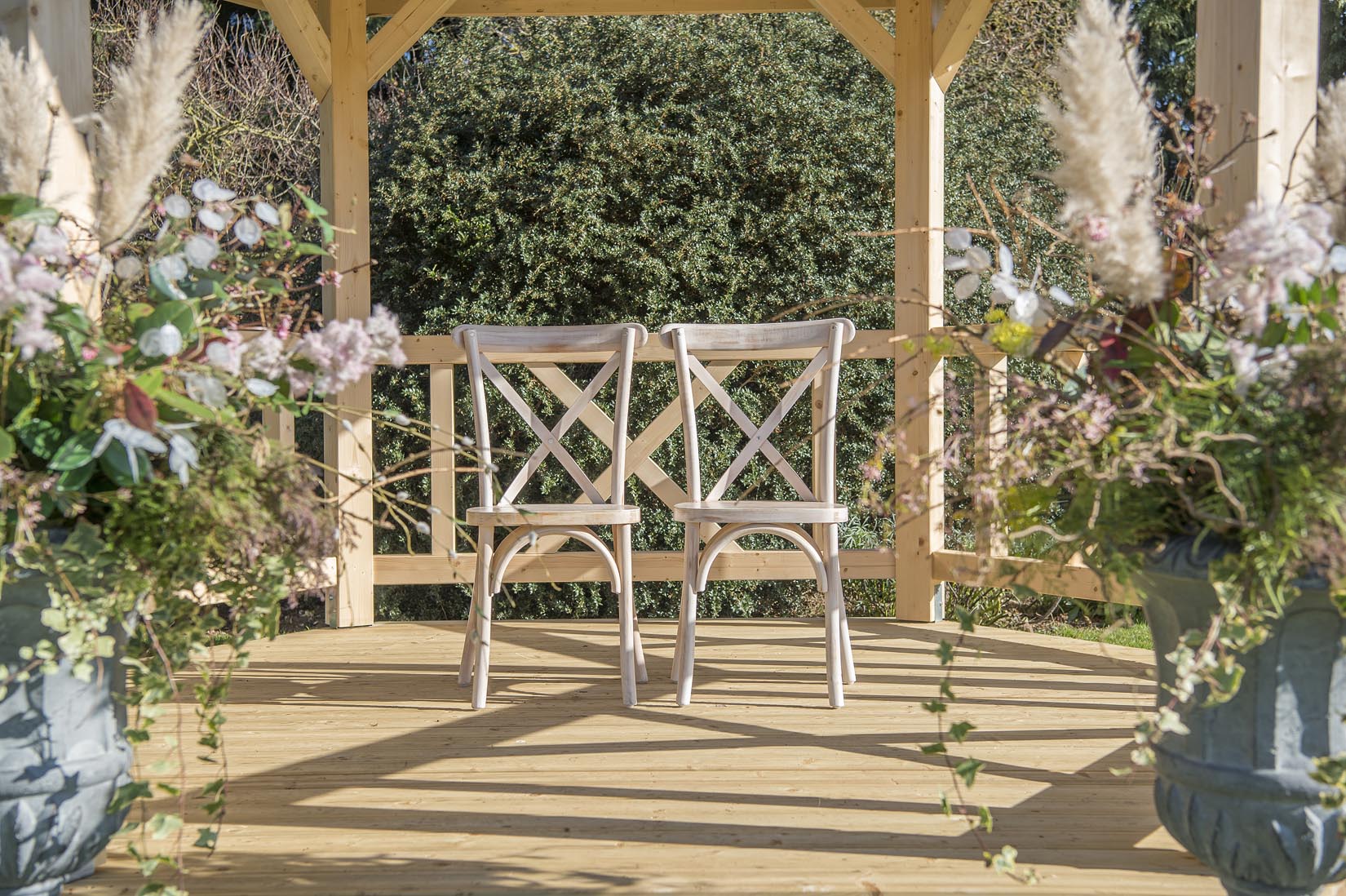 Two chairs are sitting under a gazebo decorated with flowers.