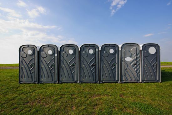 Row of Gray Portable Toilets — Station, VA — C & S Disposal A row of portable toilets for waste management services in Lynchburg, VA