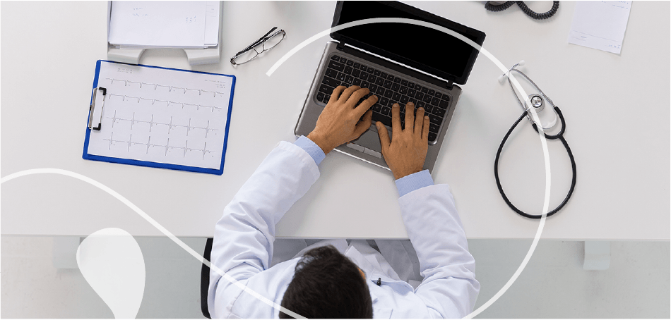 Un médico está escribiendo en una computadora portátil en un escritorio.