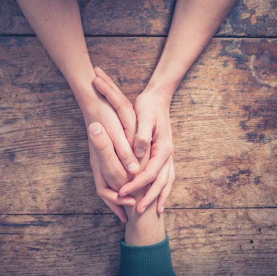 Friends holding hands while encouraging addiction recovery and lasting healing.