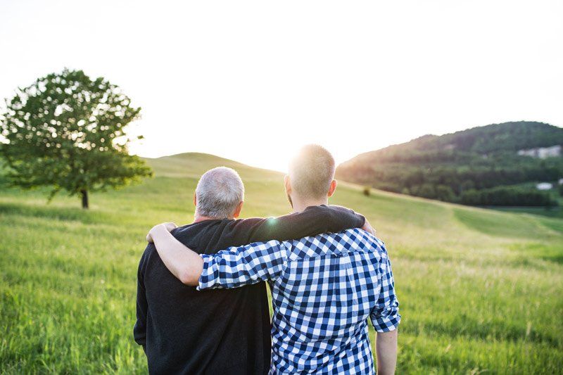 Two people standing next to each other facing a field.