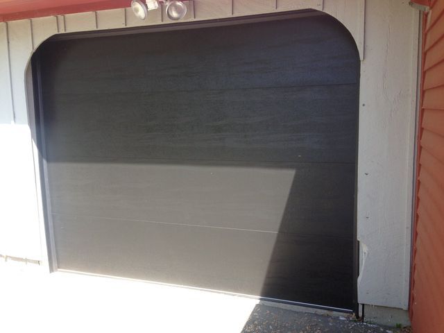 Open black garage door with gray trim and red siding.