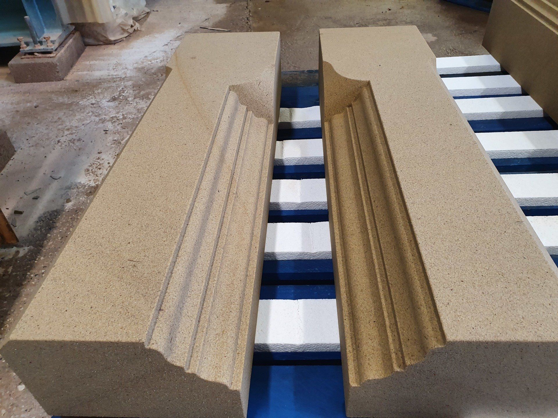 Two beige carved stone blocks with matching grooves on a blue-and-white pallet.