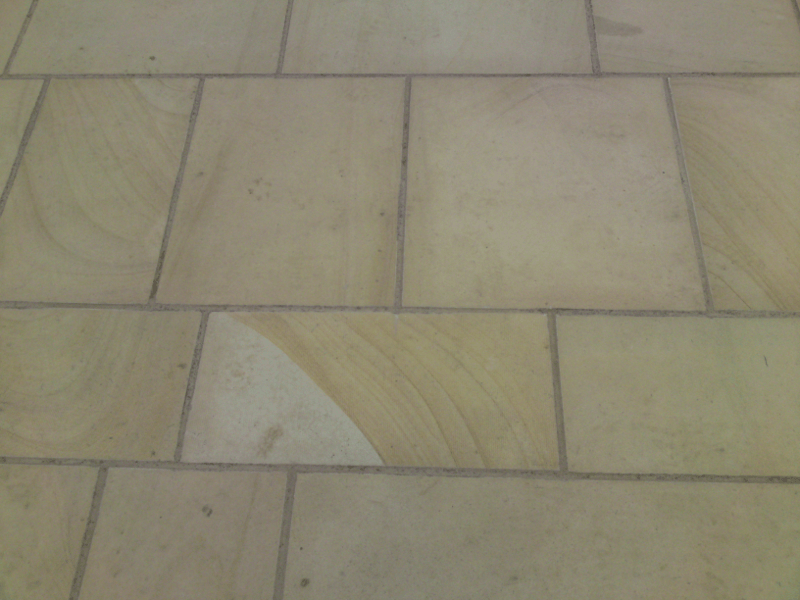 Close-up of beige patterned tile flooring with square and rectangular stone tiles.
