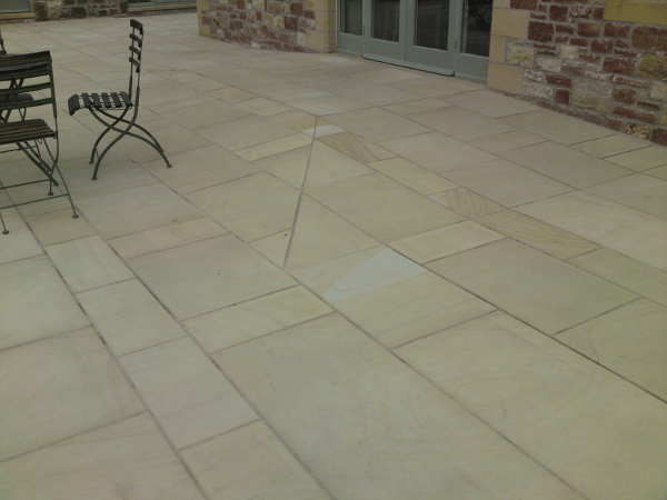Stone patio with black metal chairs beside a brick building and glass doors