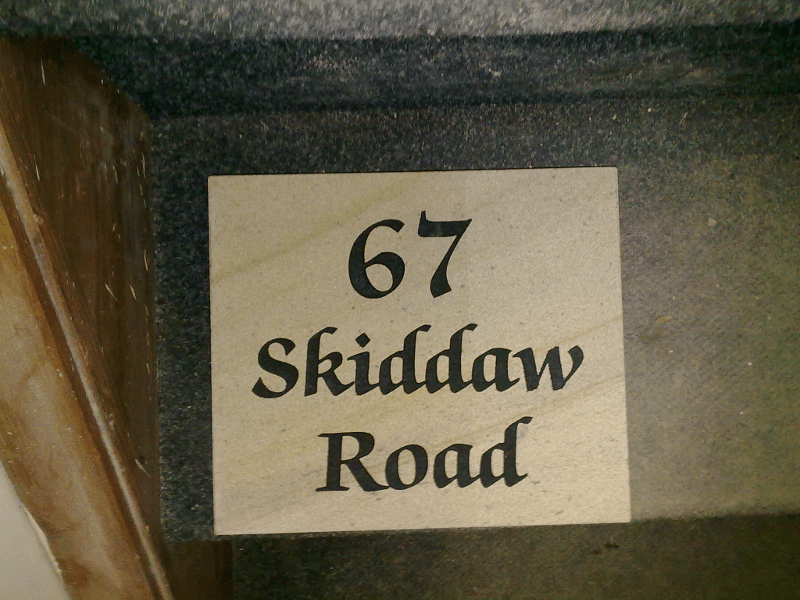 White sign reading “67 Skiddaw Road” on a dark background