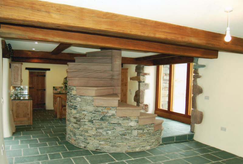 Rustic living room with stone fireplace, wood beams, and green tiled floor