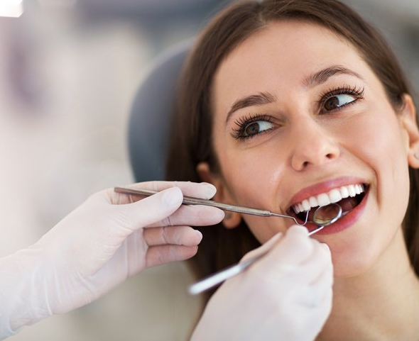 A woman is getting her teeth examined by a dentist.