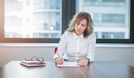 Woman looking stressed and writing on a piece of paper in a bright office - Orlando, Florida - Law Offices of Amber Jade Johnson, PA Woman looking stressed and writing on a piece of paper in a bright office - Orlando, Florida - Law Offices of Amber Jade Johnson, PA