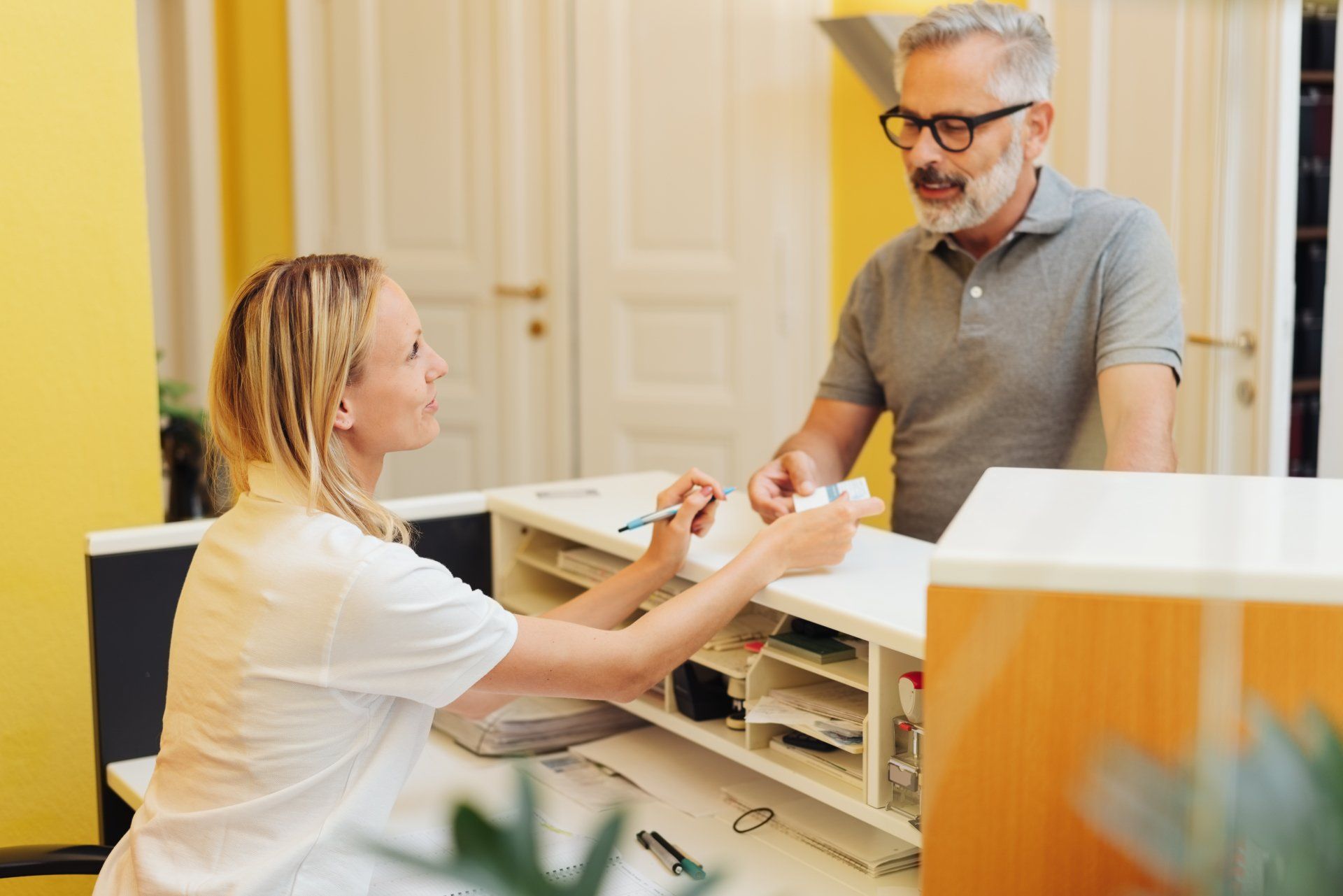 Patient settling up with a receptionist in a medical surgery after an examination by a doctor