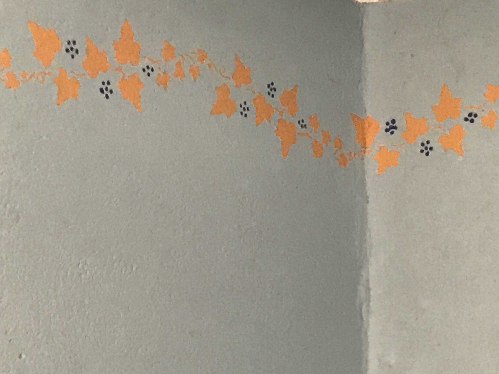 Eine graue Wand mit orangefarbenen Blumen darauf gemalt