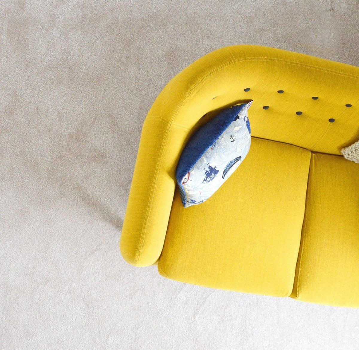 Eine gelbe Couch mit einem blauen Kissen darauf