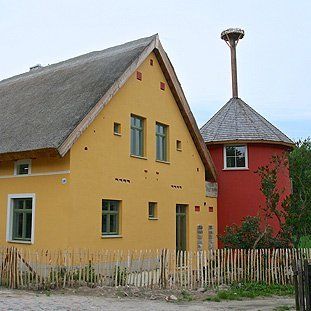 Ein gelbes Haus mit Strohdach neben einem roten Gebäude