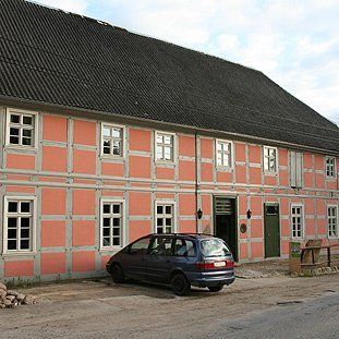 Ein blaues Auto parkt vor einem großen rosa Gebäude