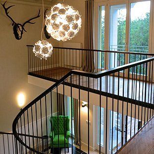 Eine Wendeltreppe in einem Haus mit einem grünen Stuhl und einem Hirschkopf an der Wand.