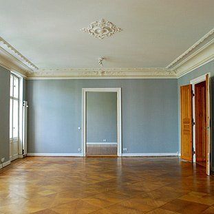 Ein leeres Wohnzimmer mit Holzboden und grauen Wänden.