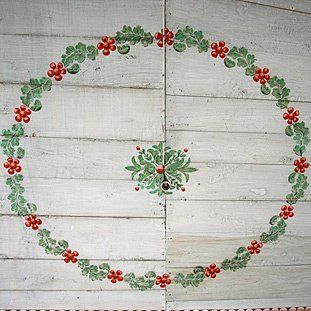Ein Kreis mit grünen Blättern und roten Blumen auf einer weißen Holzoberfläche gemalt