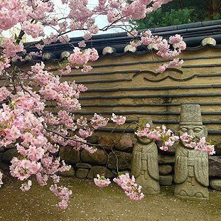 Ein paar Statuen stehen neben einem Baum mit rosa Blüten.