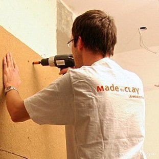Ein Mann bohrt mit einer Bohrmaschine an einer Wand.